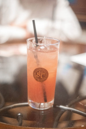 Pink cocktail in a tall Jeptha Creed glass with a straw