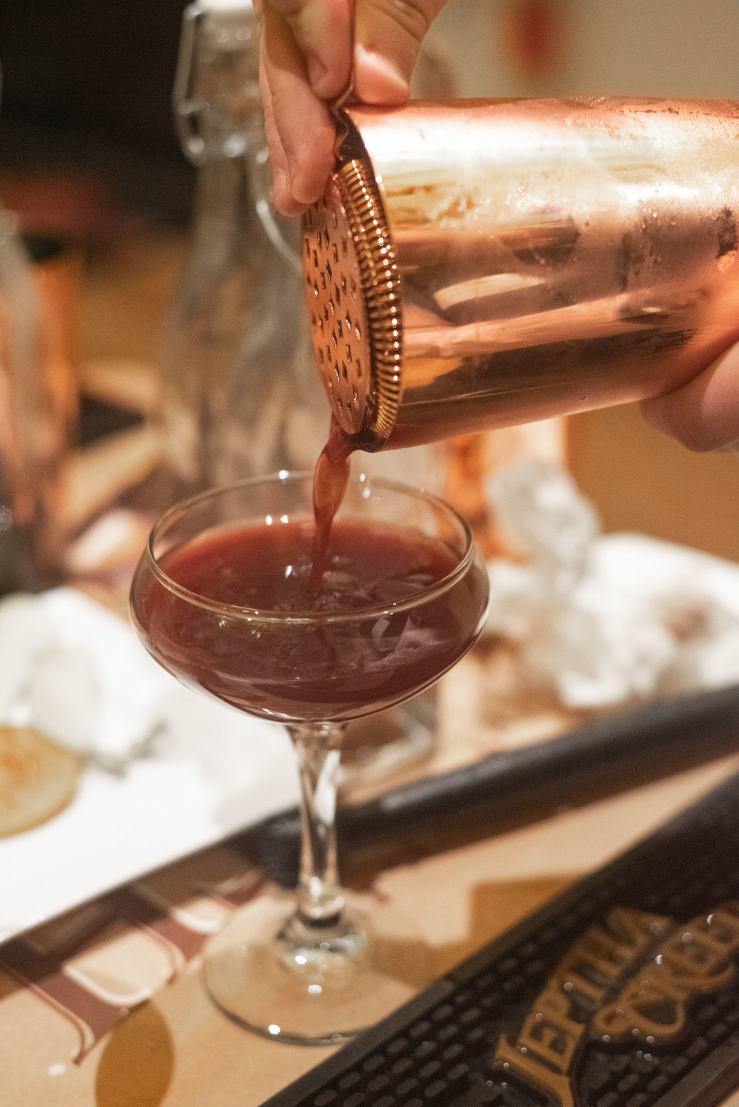 A cocktail being poured into a glass