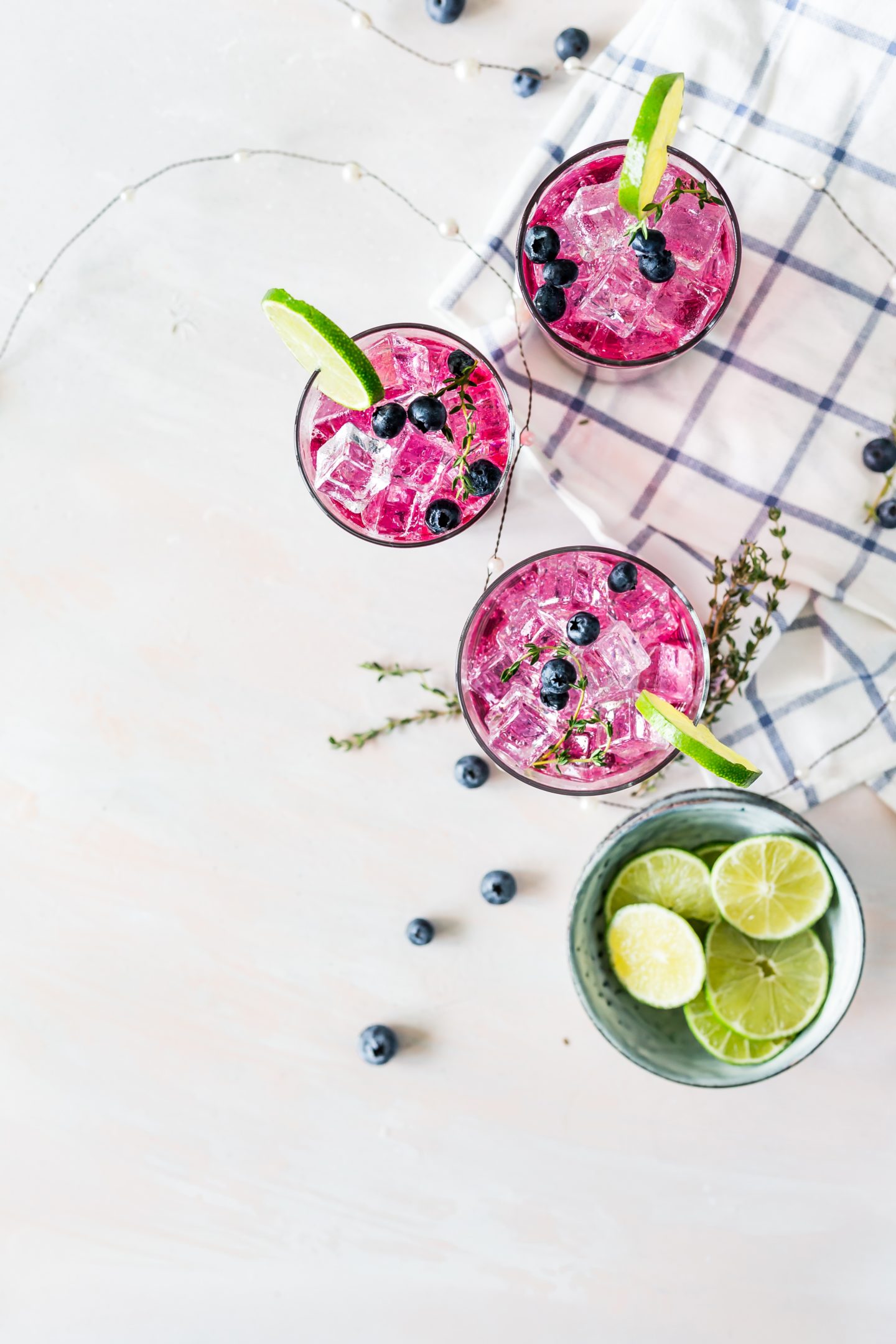 Three pink drinks in glasses with lime and one green drink with in a glass with limes