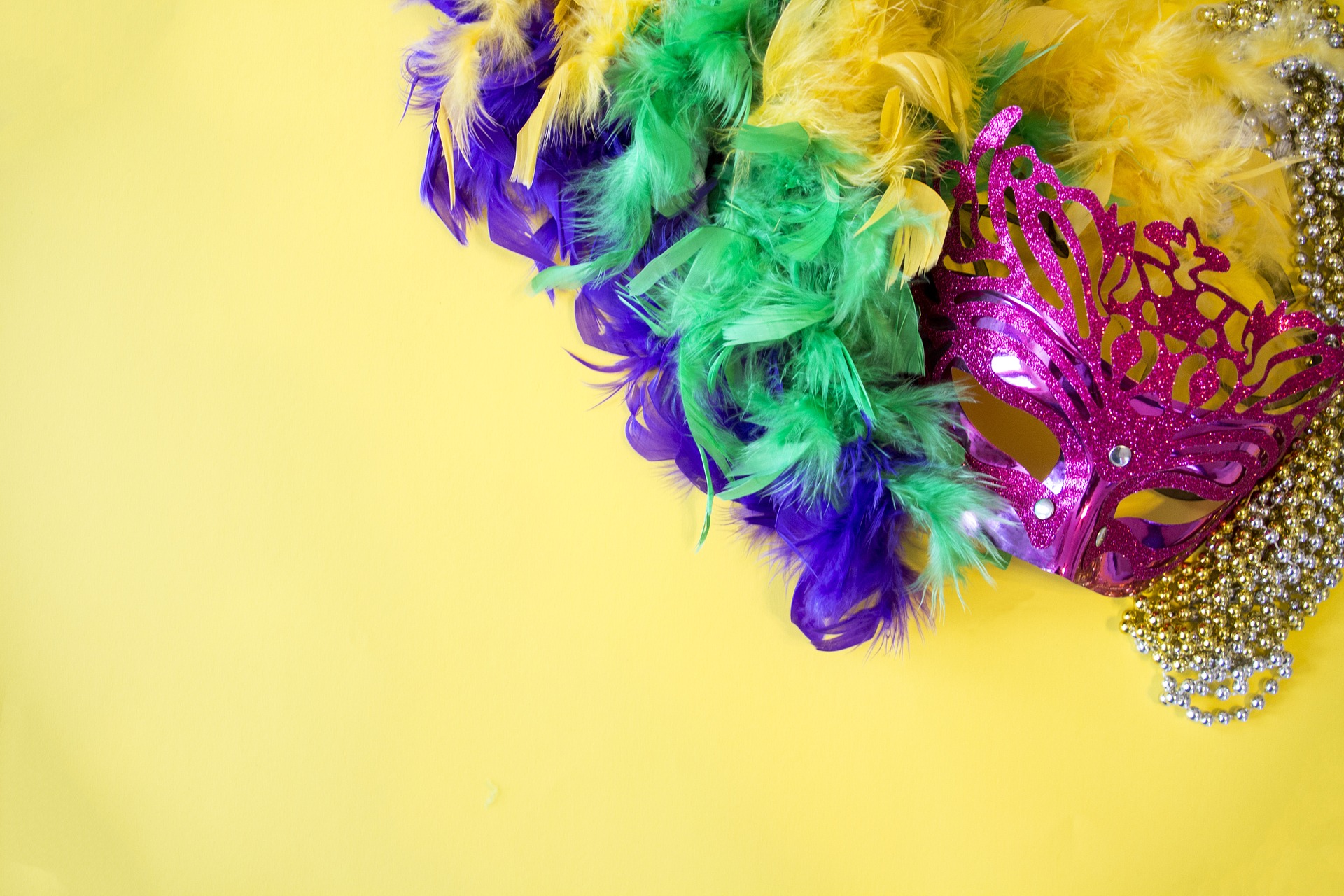 Colorful Mardi Gras mask with a boa on a yellow background