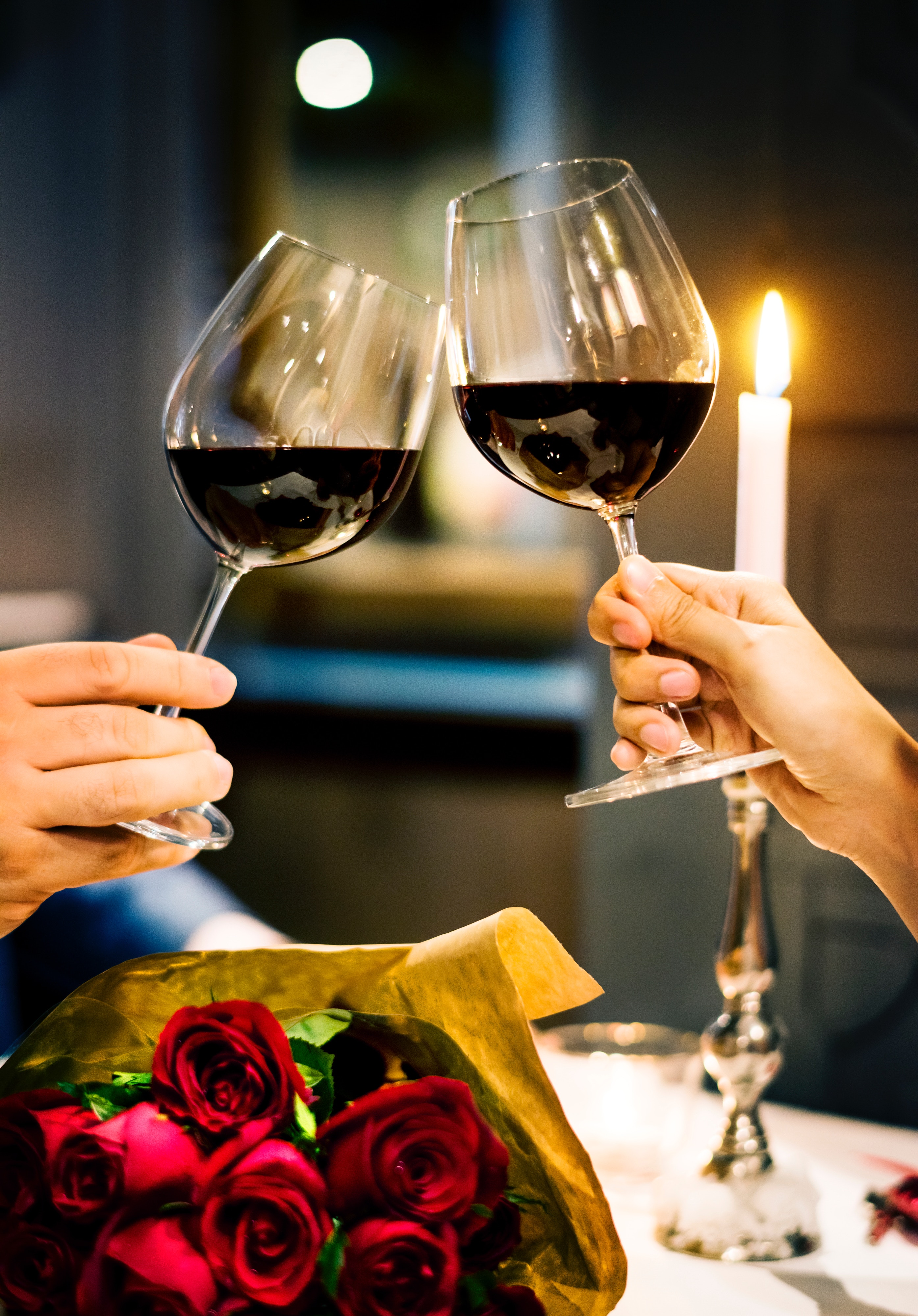 Two wine glasses clinking over a candlelight dinner