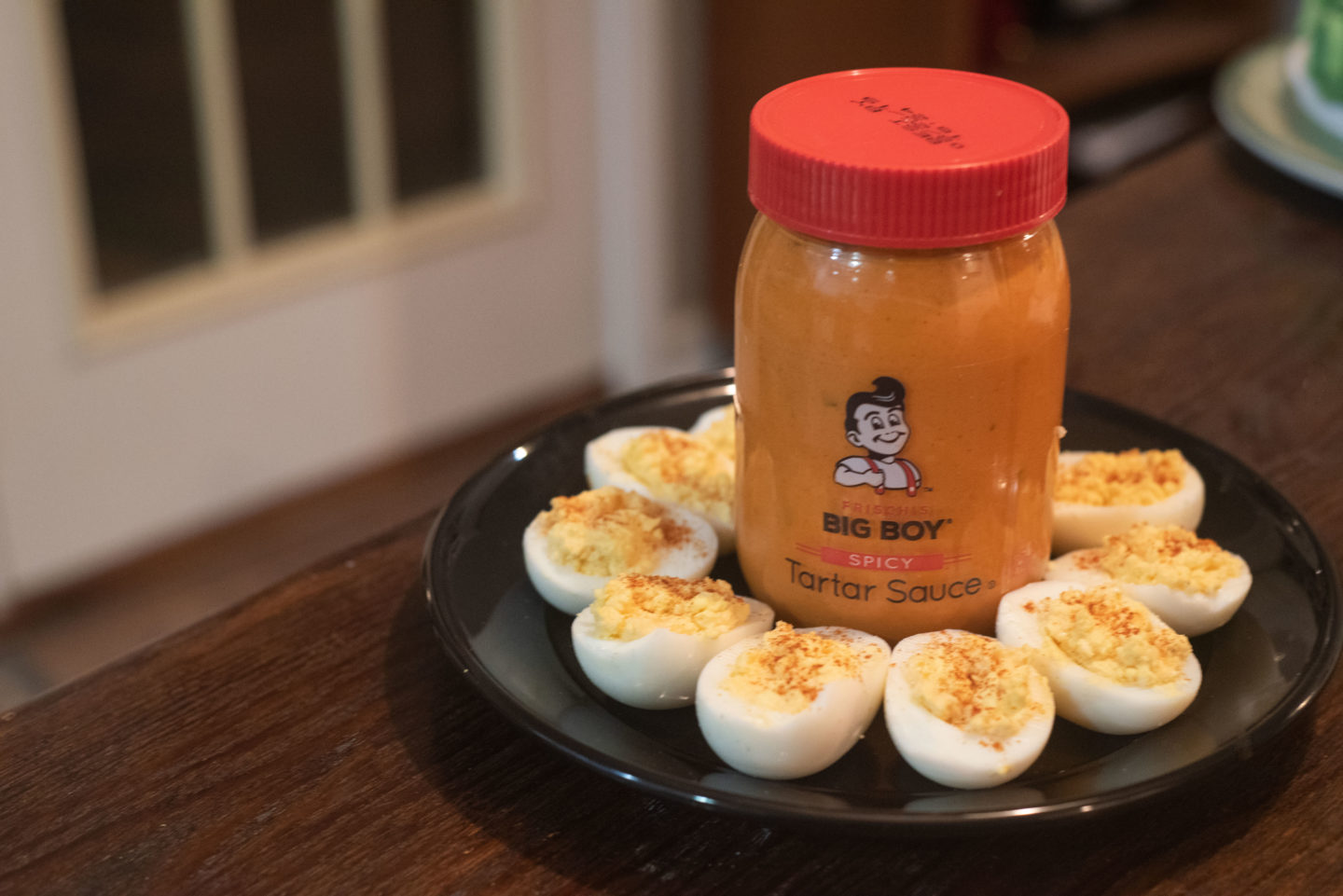 Deviled Eggs sitting on a black plate with a jar of Frisch's Spicy Tartar Sauce