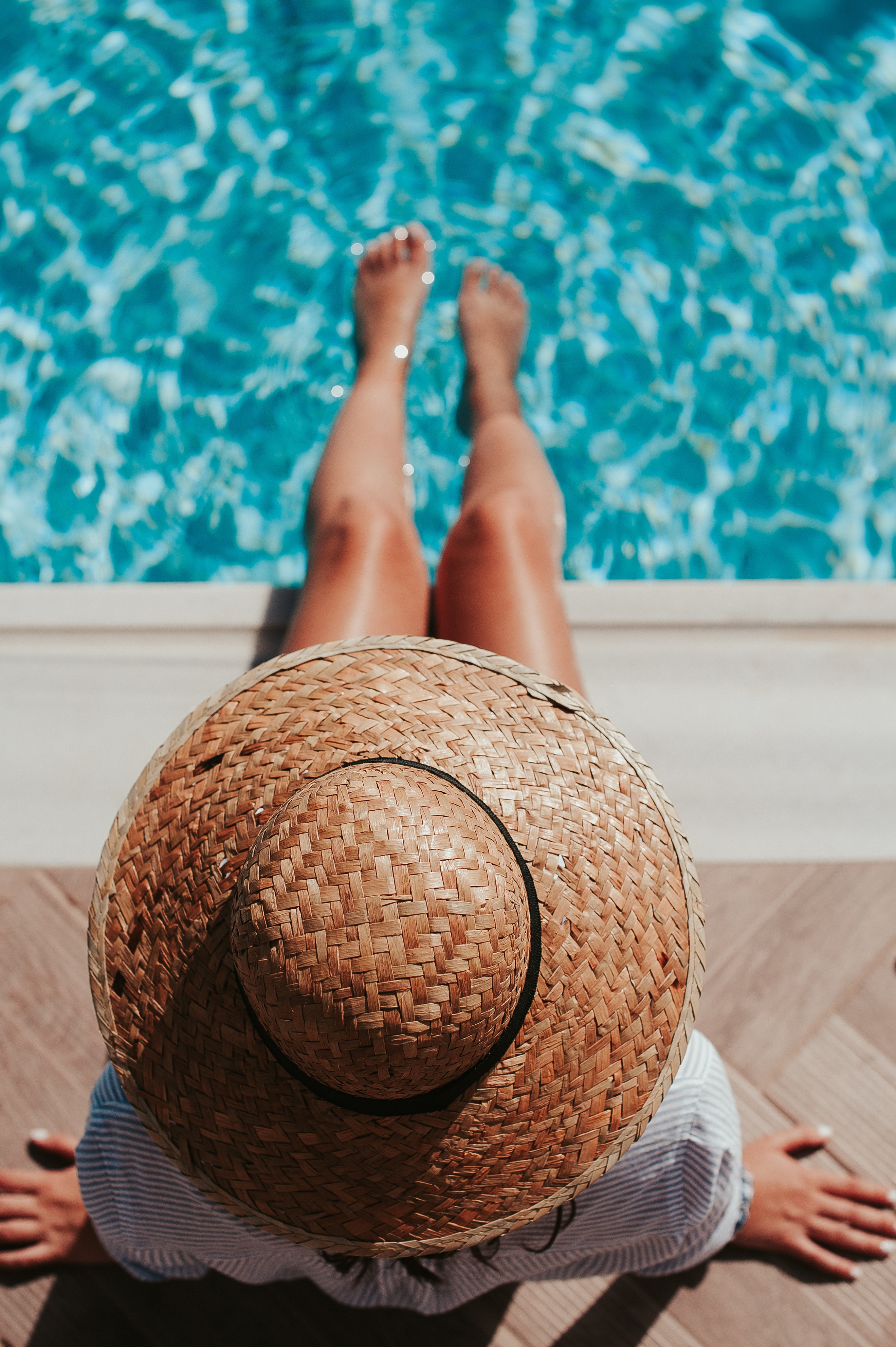 Girl in a hat with her legs in a pool