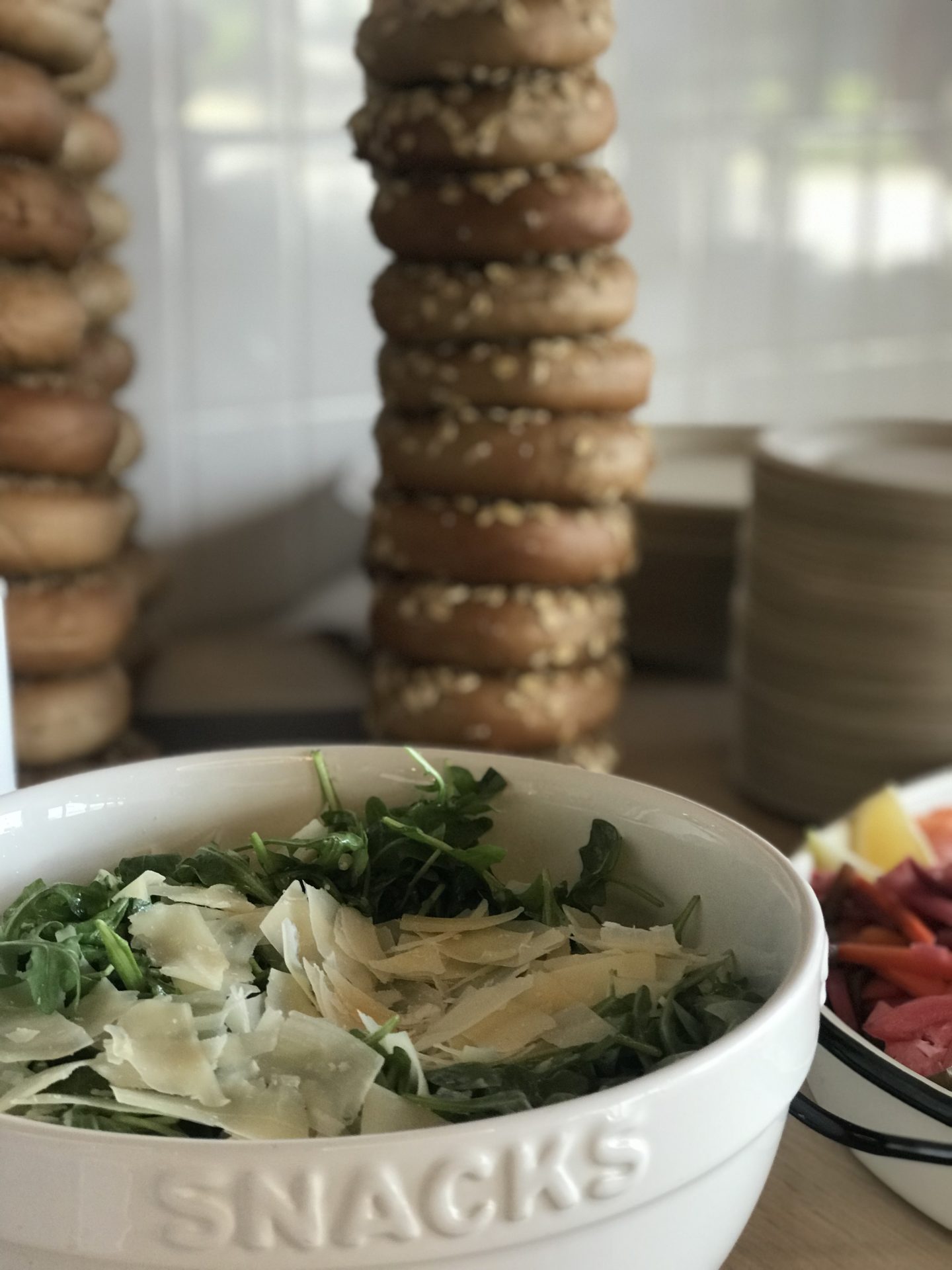 Greens and cheese with bagels in the background