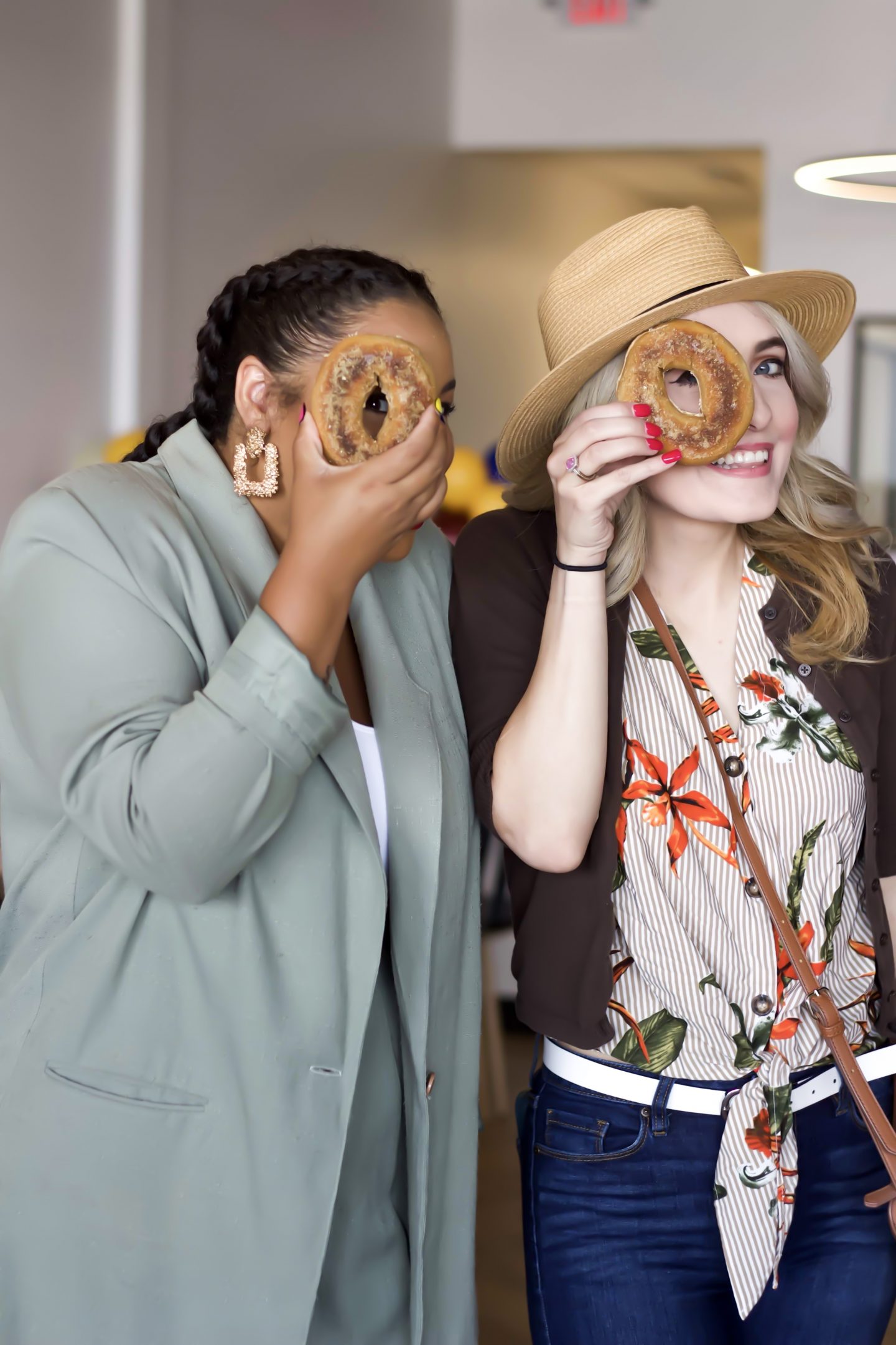 Two girls holding a bagel up to their eye