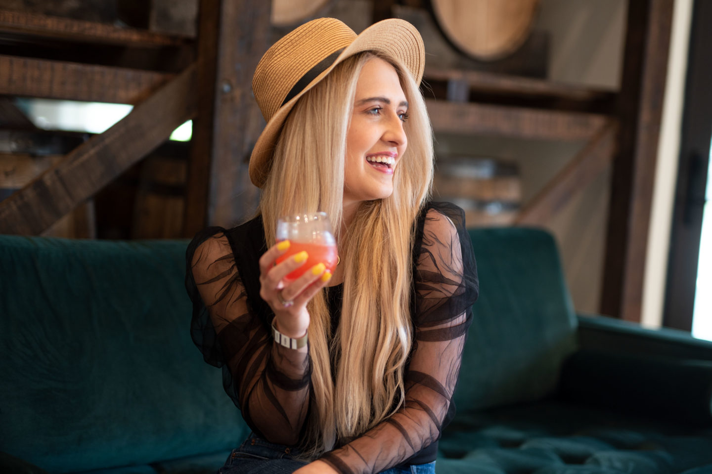 girl in a hat holding a drink smiling