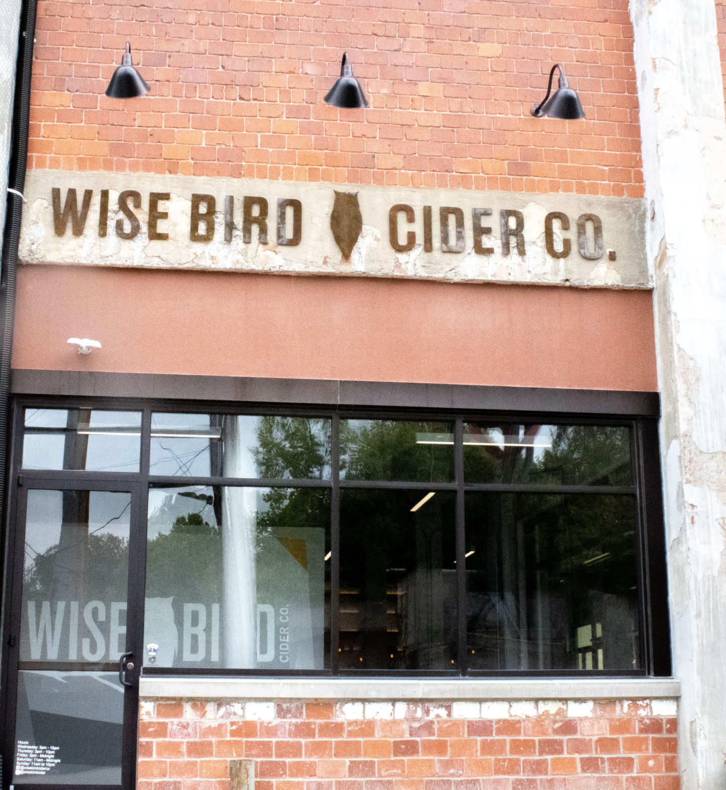 the front of a brick building with the sign wise bird cider co